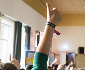 Jugendliche stimmen per Handzeichen zu Themen im großen Saal ab.