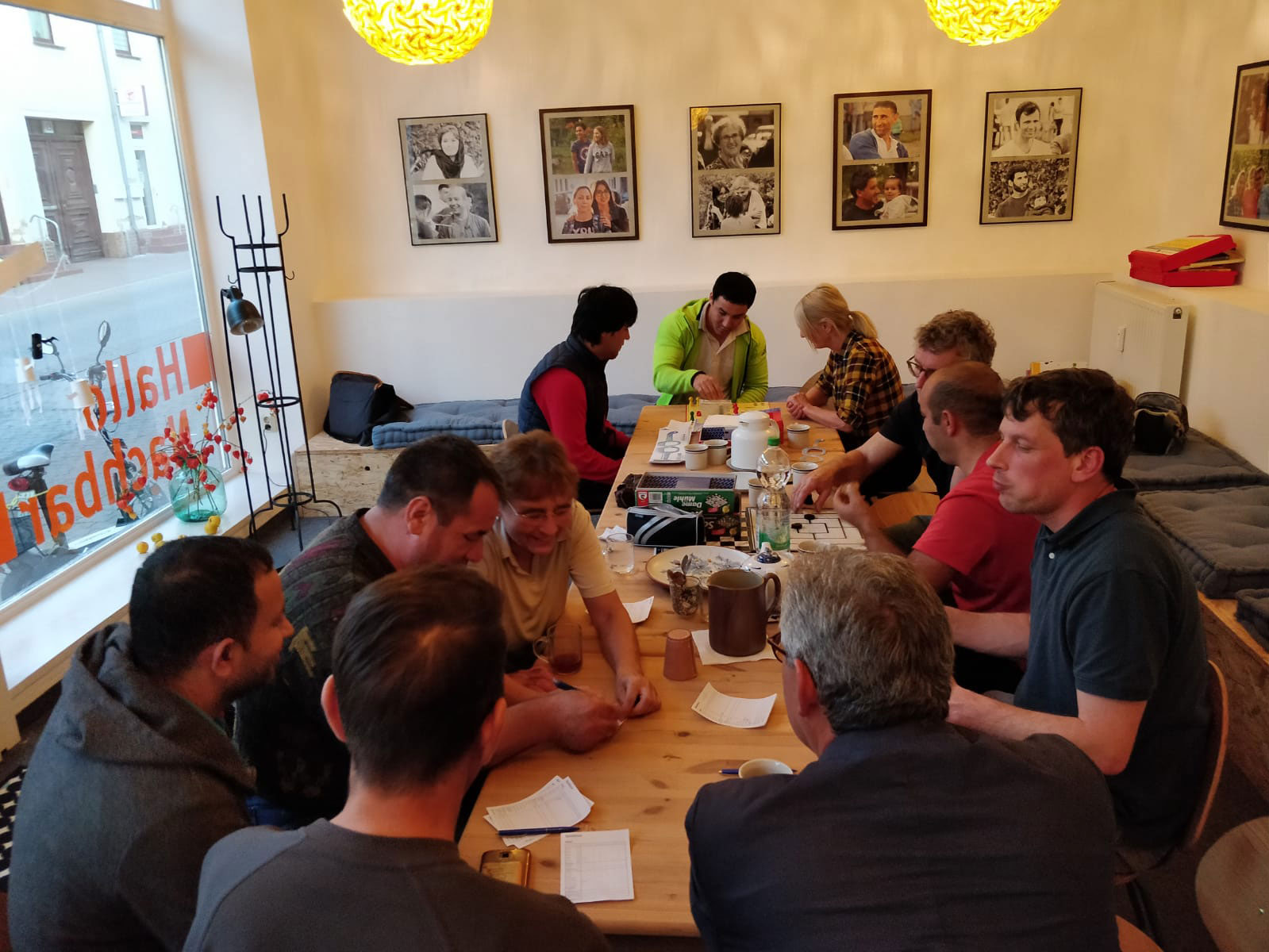 Menschen sitzen an einer langen Tafel im Stadtteilladen Hallo Nachbar in Zehdenick zusammen und spielen Spiele.