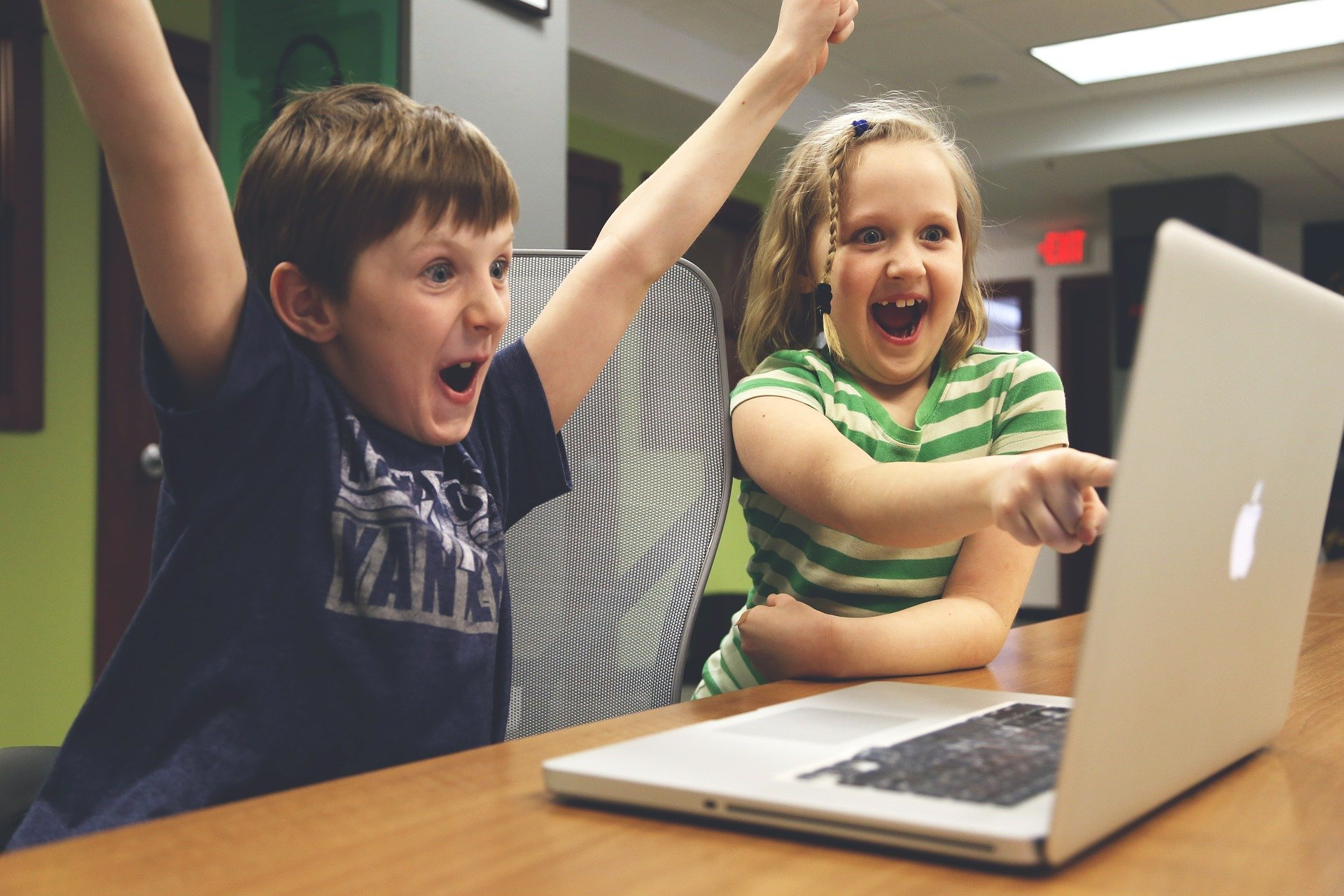 Zwei begeisterte Kinder, die vor einem Laptop sitzen. Zugang zur Bildung für alle. Spendet Laptops.