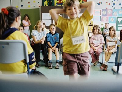 Das Foto zeigt eine Gruppe Kinder in einer spielerischen Workshopsituation.